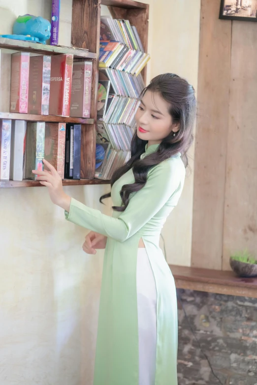 a woman with a green and white dress standing in front of bookshelves