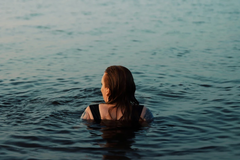 a woman standing in the water in front of a body of water