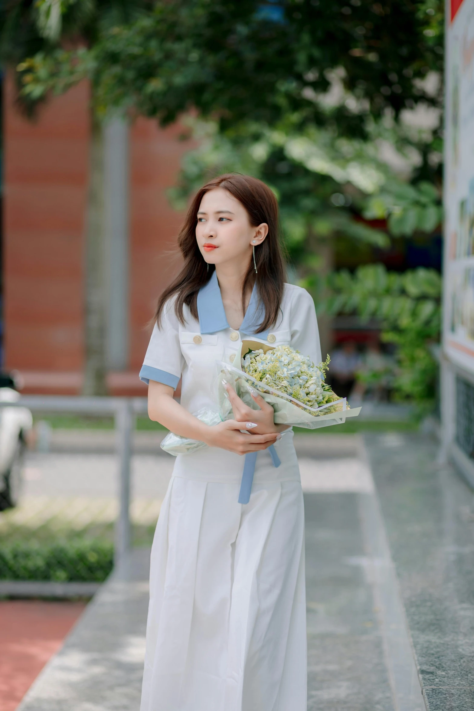 a woman dressed in white holding flowers on the street
