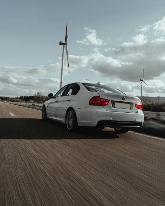 white bmw with chrome accents driving down an asphalt road