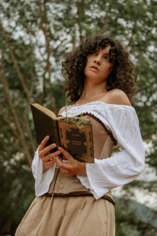 a women in a white shirt is holding a book