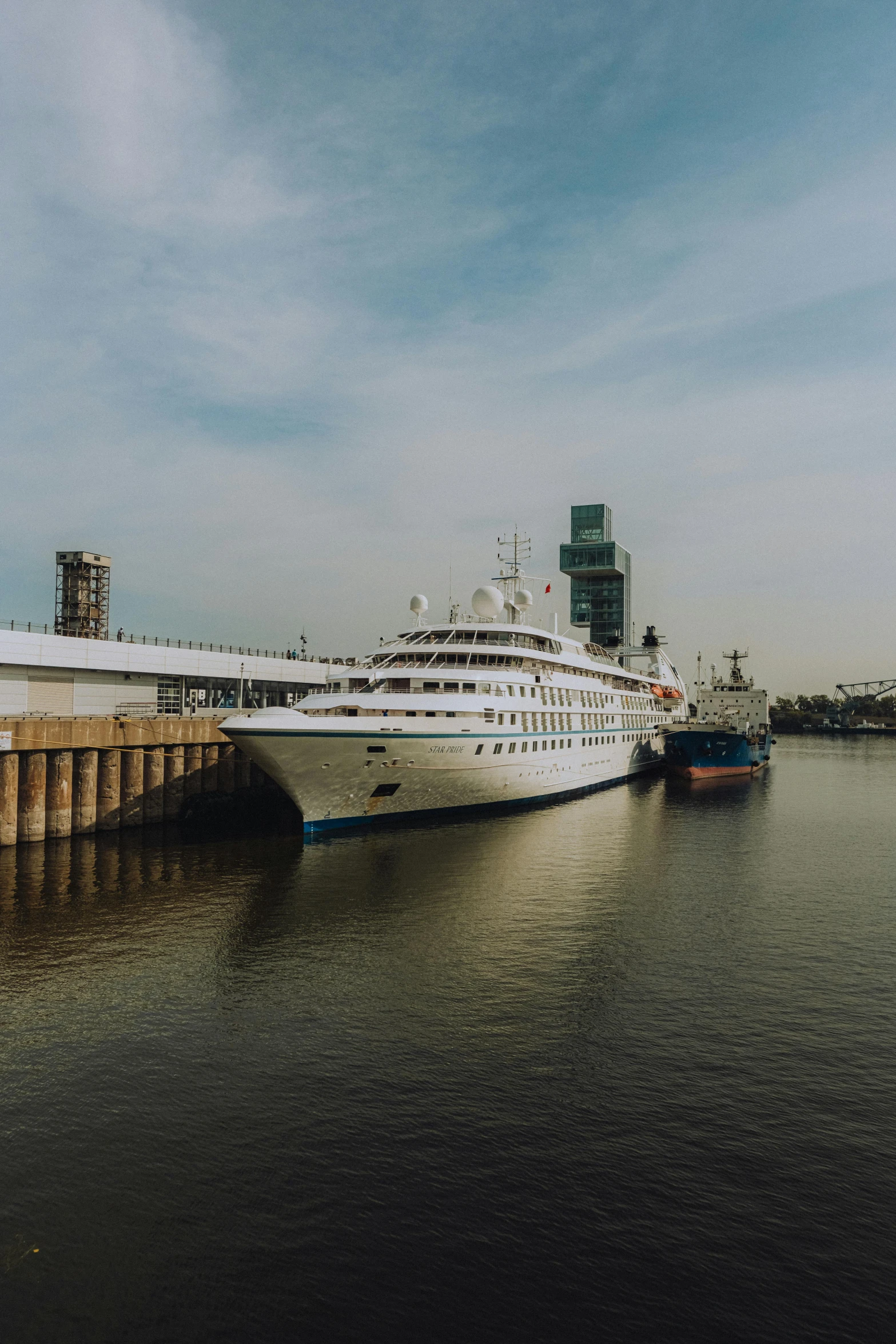 two cruise ships docked in the water in front of a wooden pier