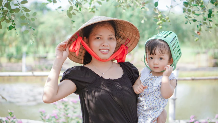 a woman holding onto her child wearing a large hat