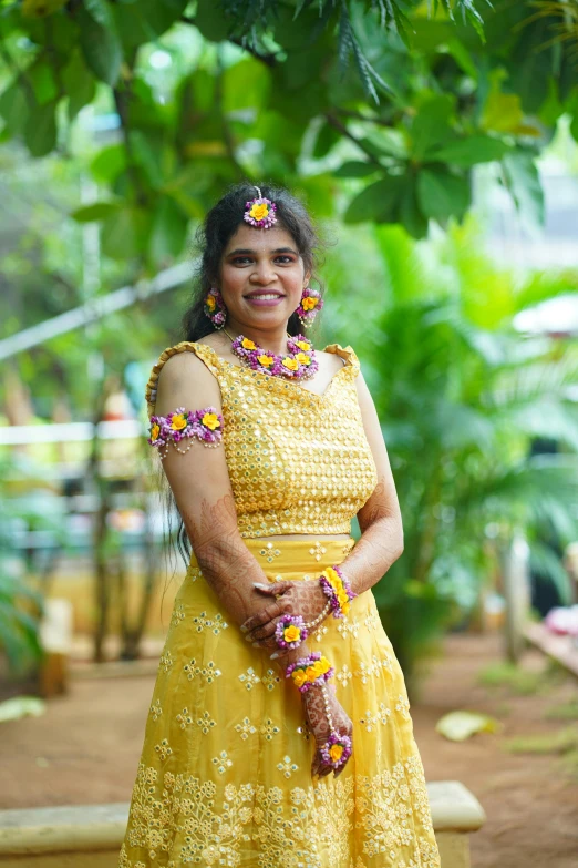 a smiling woman in yellow stands under a tree