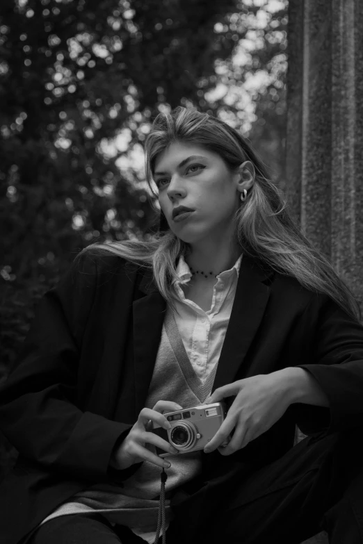 a woman sitting in the forest with her camera