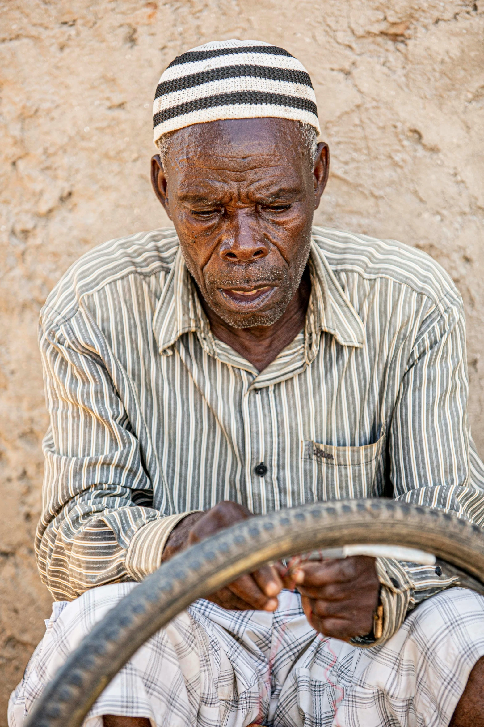 a man with striped shirt and cap on driving a small vehicle