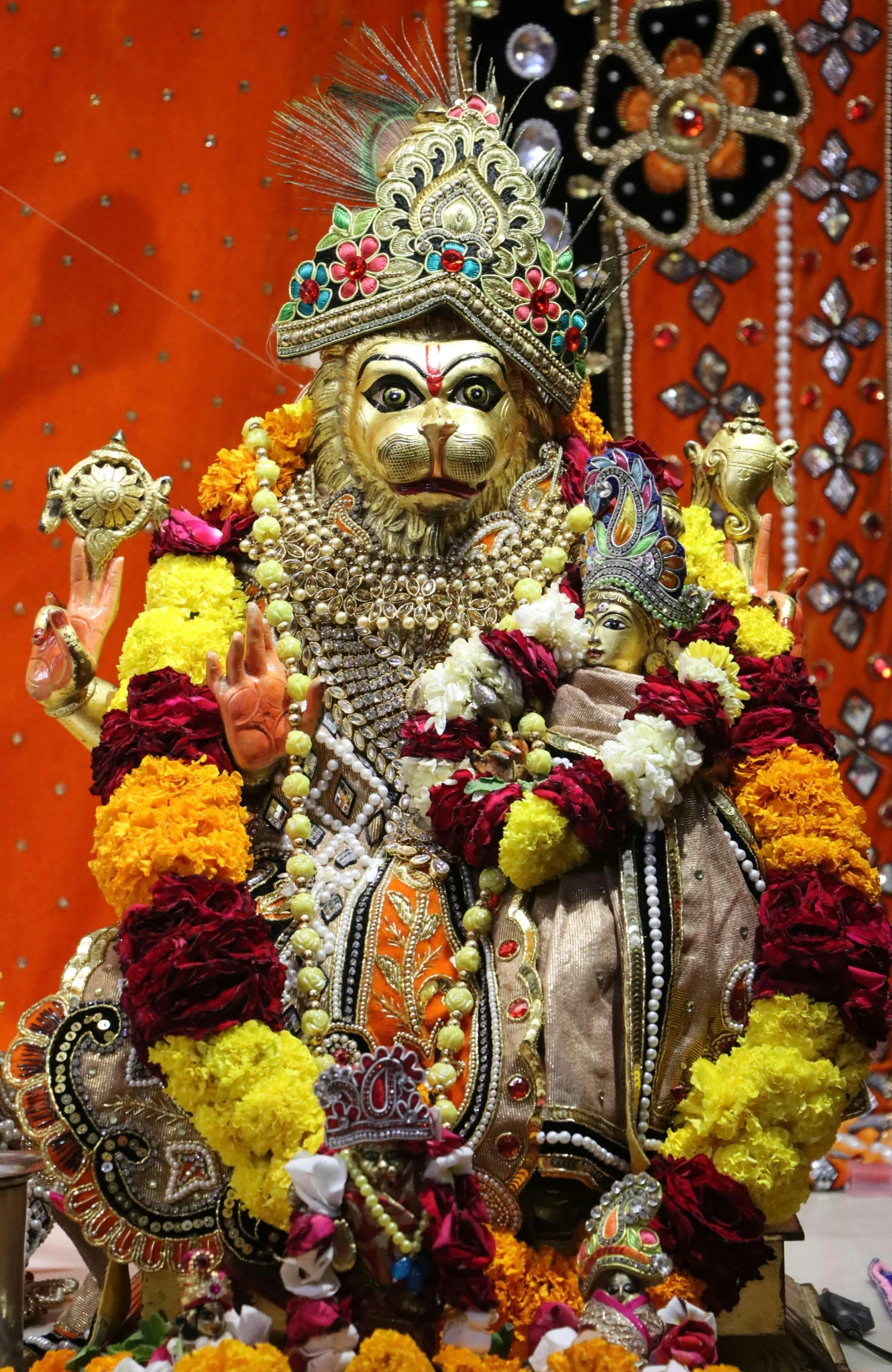 statue of hindu god with decorative costume on orange and yellow stage backdrop