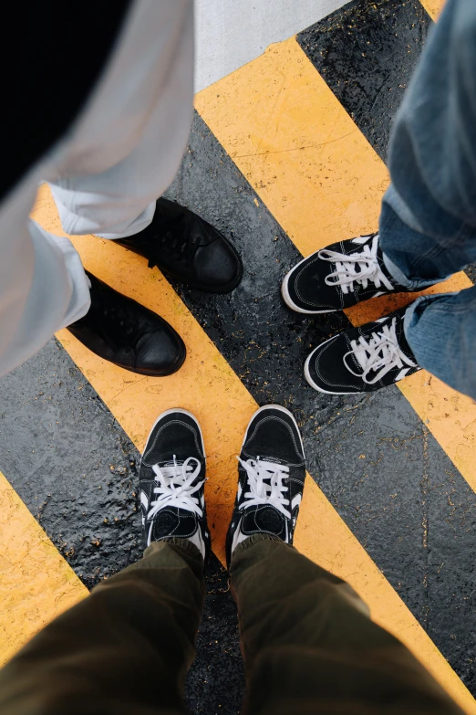 two men with black shoes standing in a yellow and black crosswalk