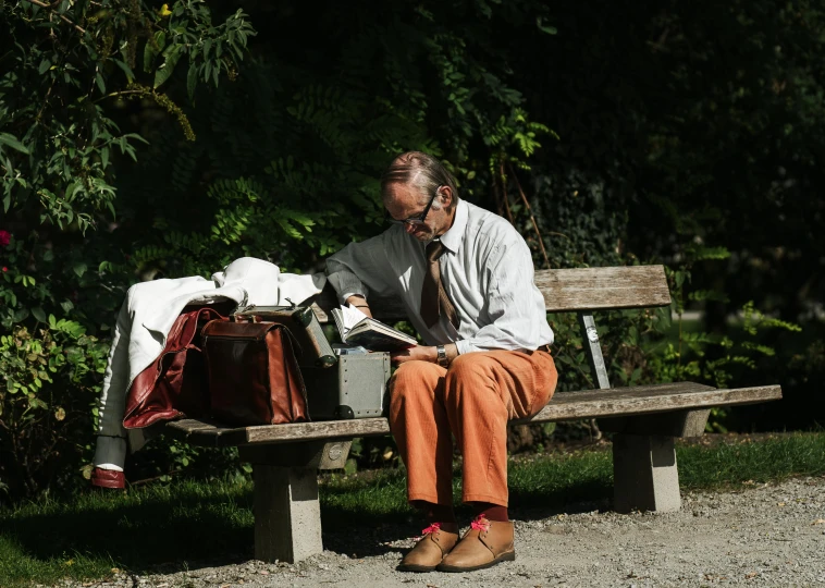 a man is sitting on a bench reading a newspaper