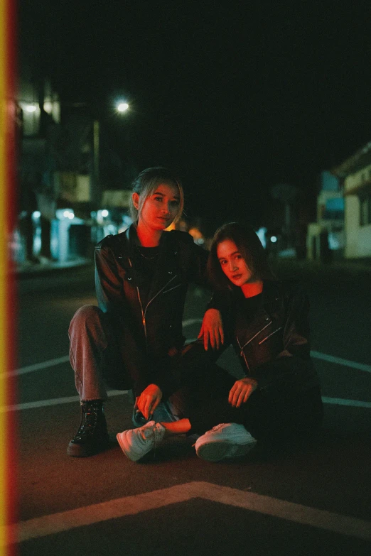 two men sitting on a curb by the street at night