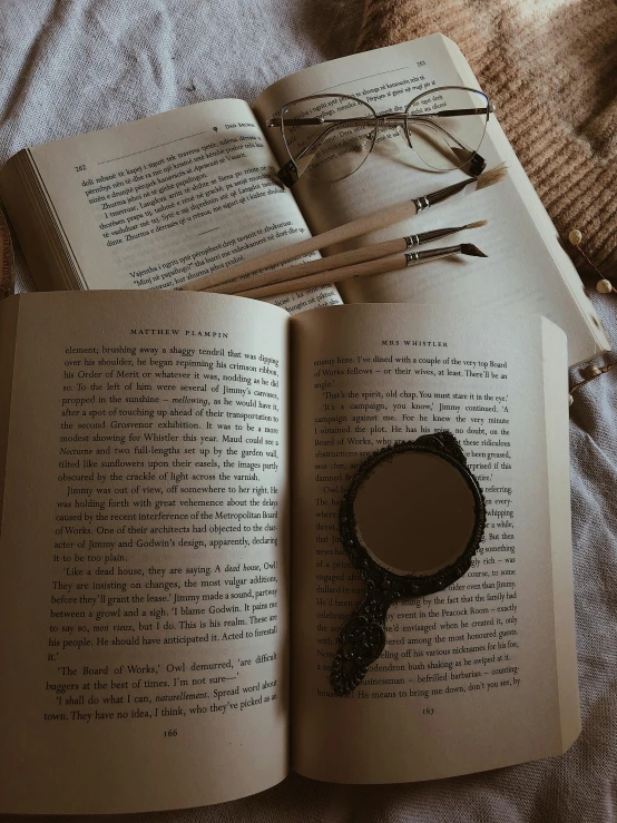 a magnifying glass and two pencils are lying on an open book