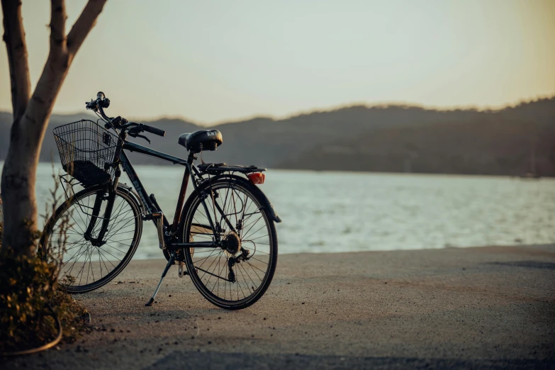 the bike is parked near the water on the shore