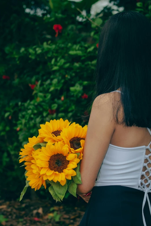 the woman is holding a bouquet of sunflowers
