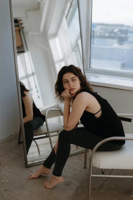 woman sitting on stool looking at herself in mirror