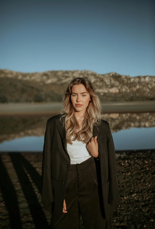 woman in a white shirt and dark brown jacket standing outside