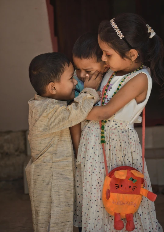 two young children touching the face of a little girl