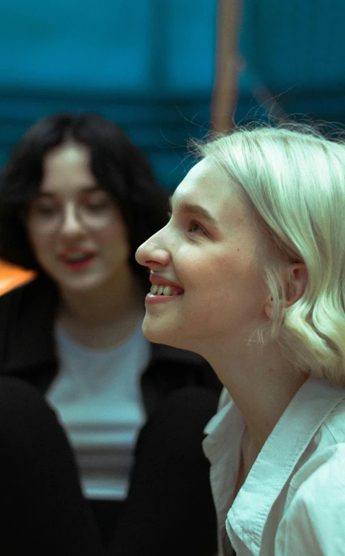 a woman sitting next to another woman with her chin hanging out