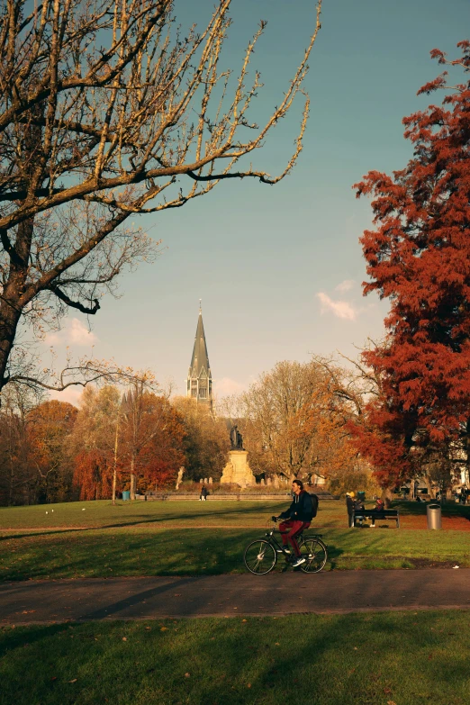 a person on a bike sitting in a park with a large tower