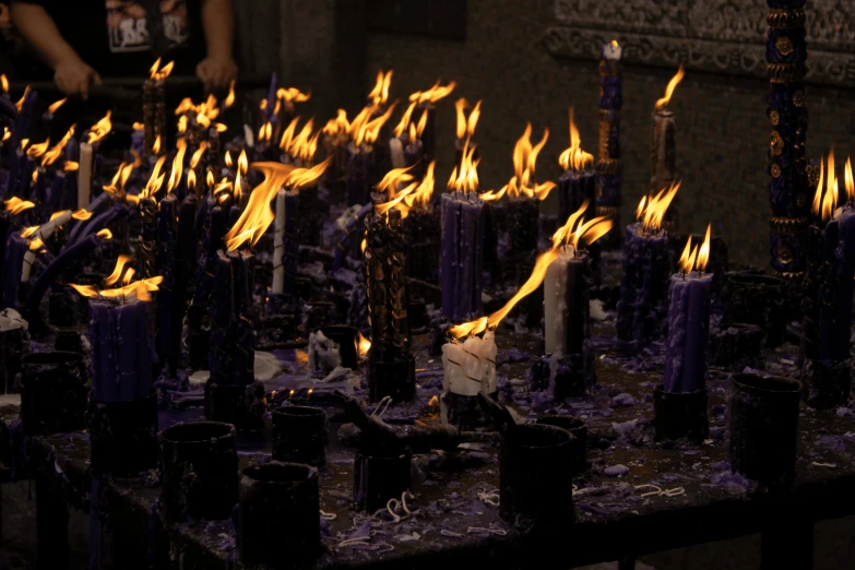 a table with many candles and a person looking over it