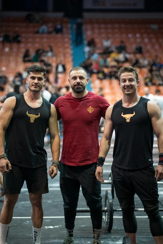 three men standing on a weight scale in front of a stadium