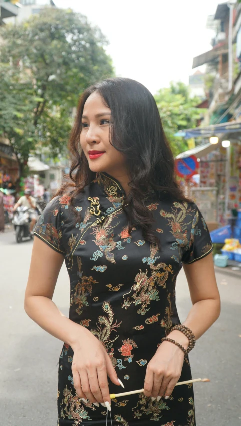 an asian woman in a black dress is holding a cane