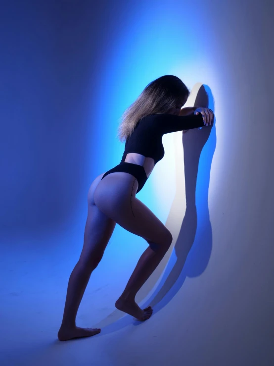 a person bending over in underwear leaning on a wall