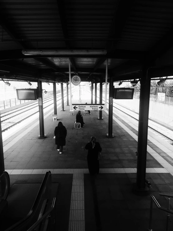 people walking through the railway platform under a covering