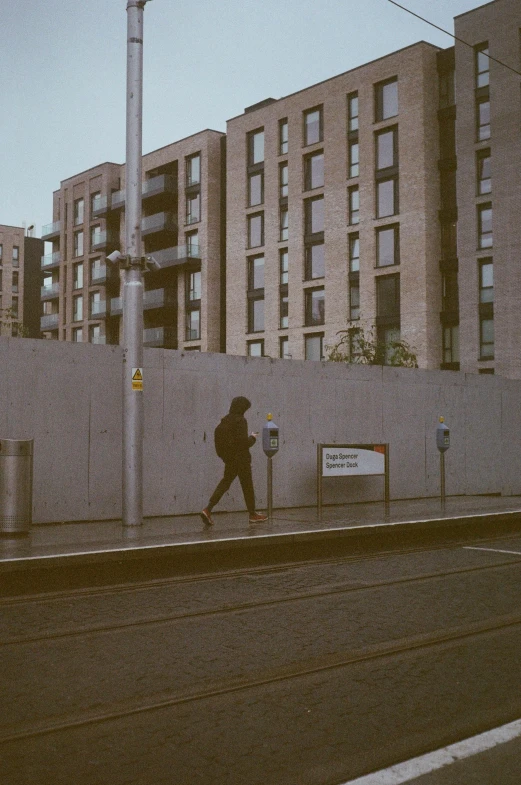 a woman walking past a high rise building on a sidewalk