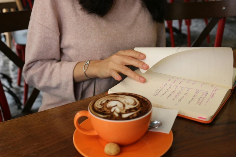 a woman with a cappuccino next to a book and a coffee