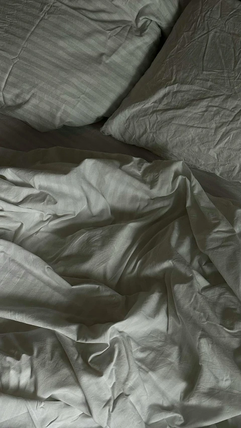 an unmade bed covered in white linen