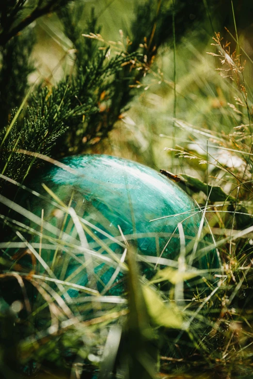 a green glass ornament is placed in the grass