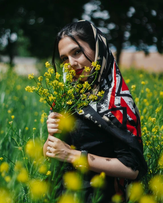 a woman is holding flowers in the middle of a field