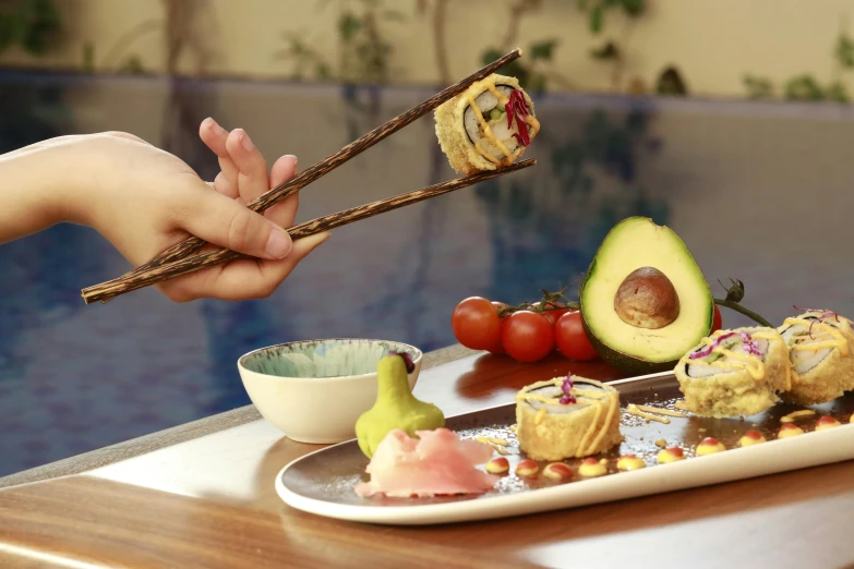 a man is holding two chopsticks over small sushi