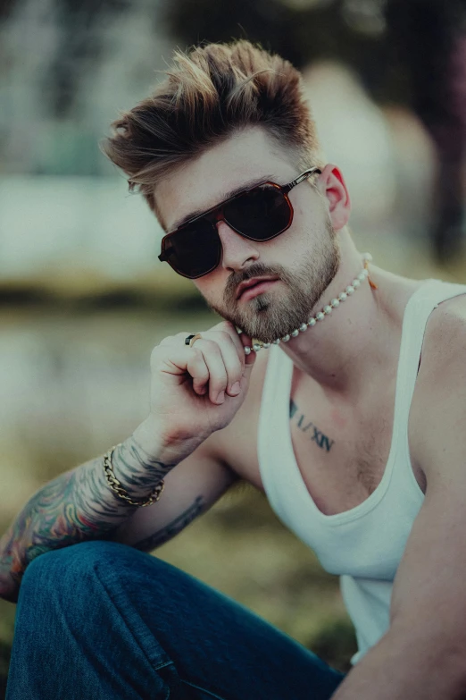 a man with glasses and piercings sitting on the ground