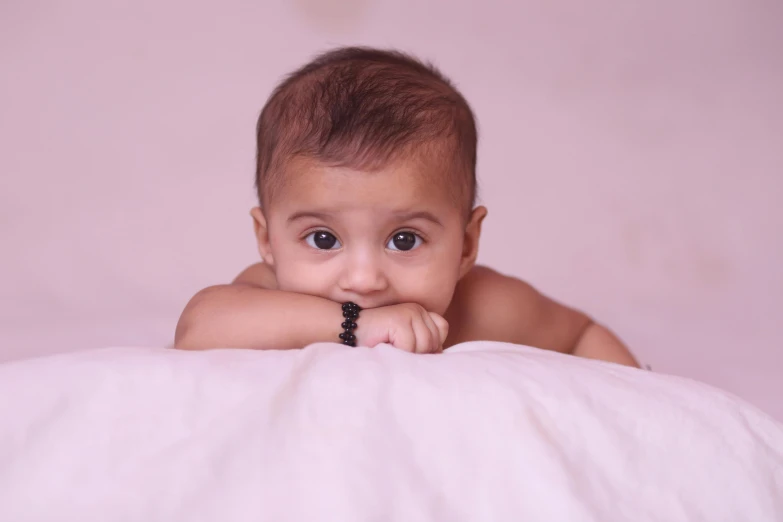 a baby with a black nose is peeking over the edge of a blanket