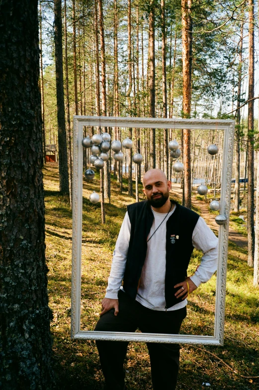 a man wearing a vest and holding a framed po