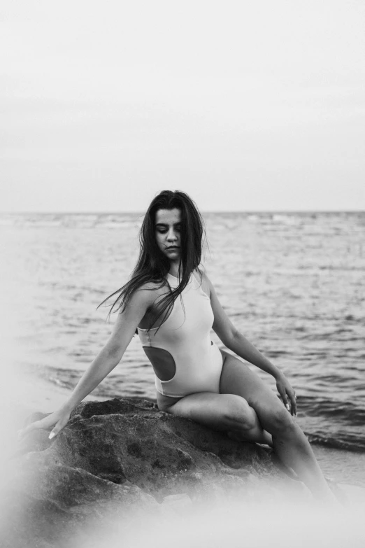 a woman sitting on top of a rock by the ocean