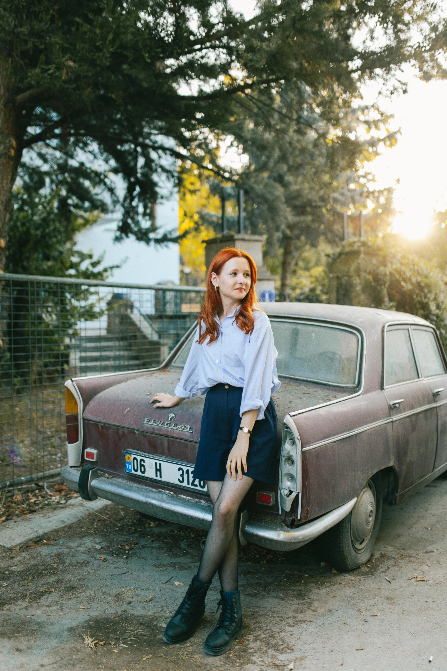 a girl is sitting on the bumper of an old car