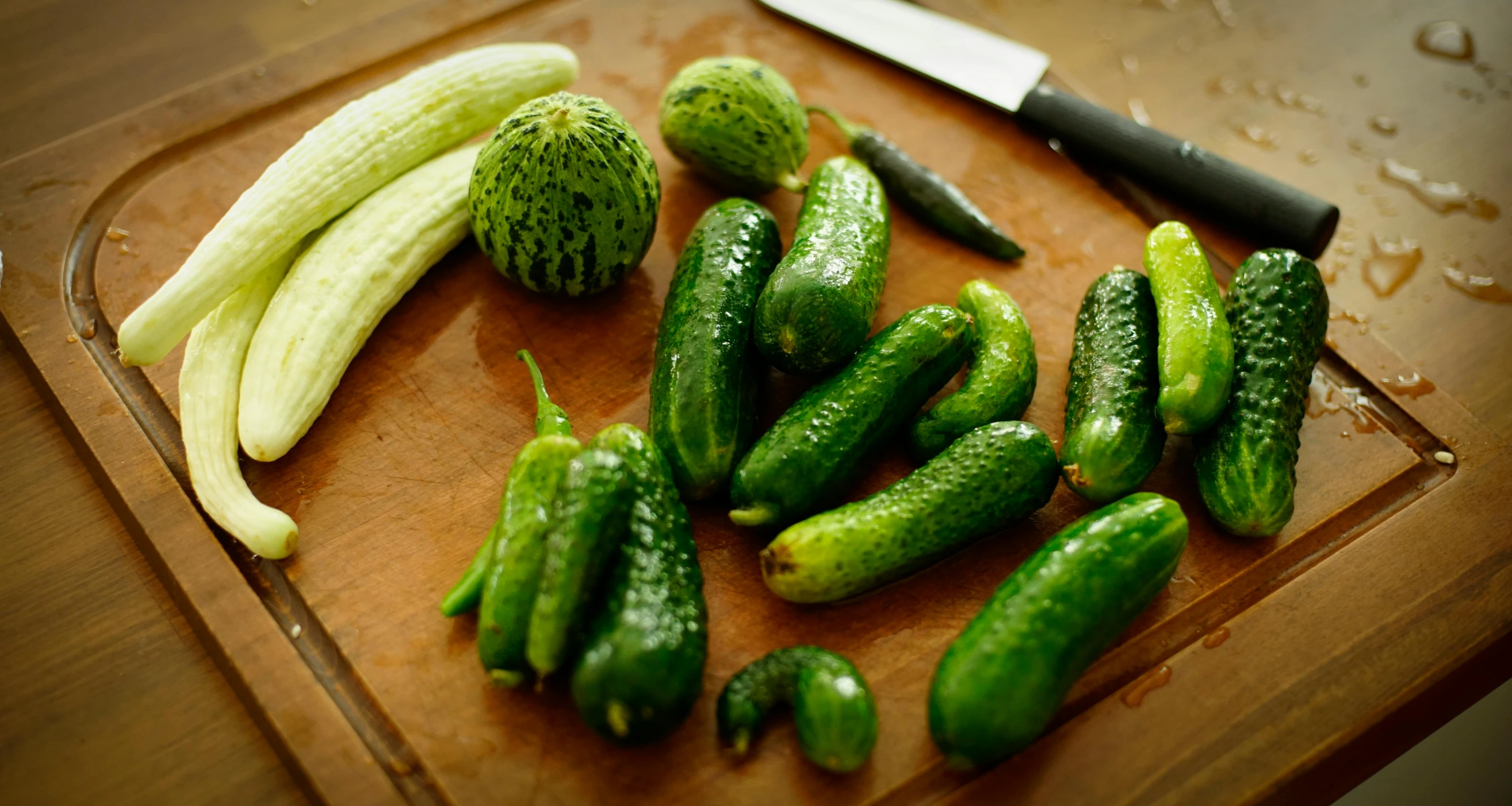 a  board with cucumbers and a knife