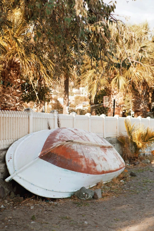 an old worn boat sitting out by a fence