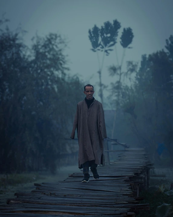 a man in coat standing on wooden walkway