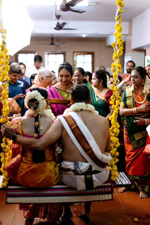 indian bride sits on a swing surrounded by other people