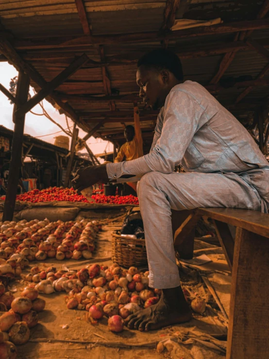 man sitting on the top of an outdoor bench near many onions