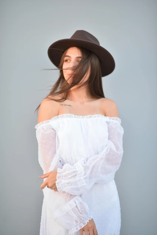 a woman wearing a hat standing next to a gray wall