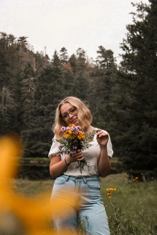 a woman with flowers standing in a field