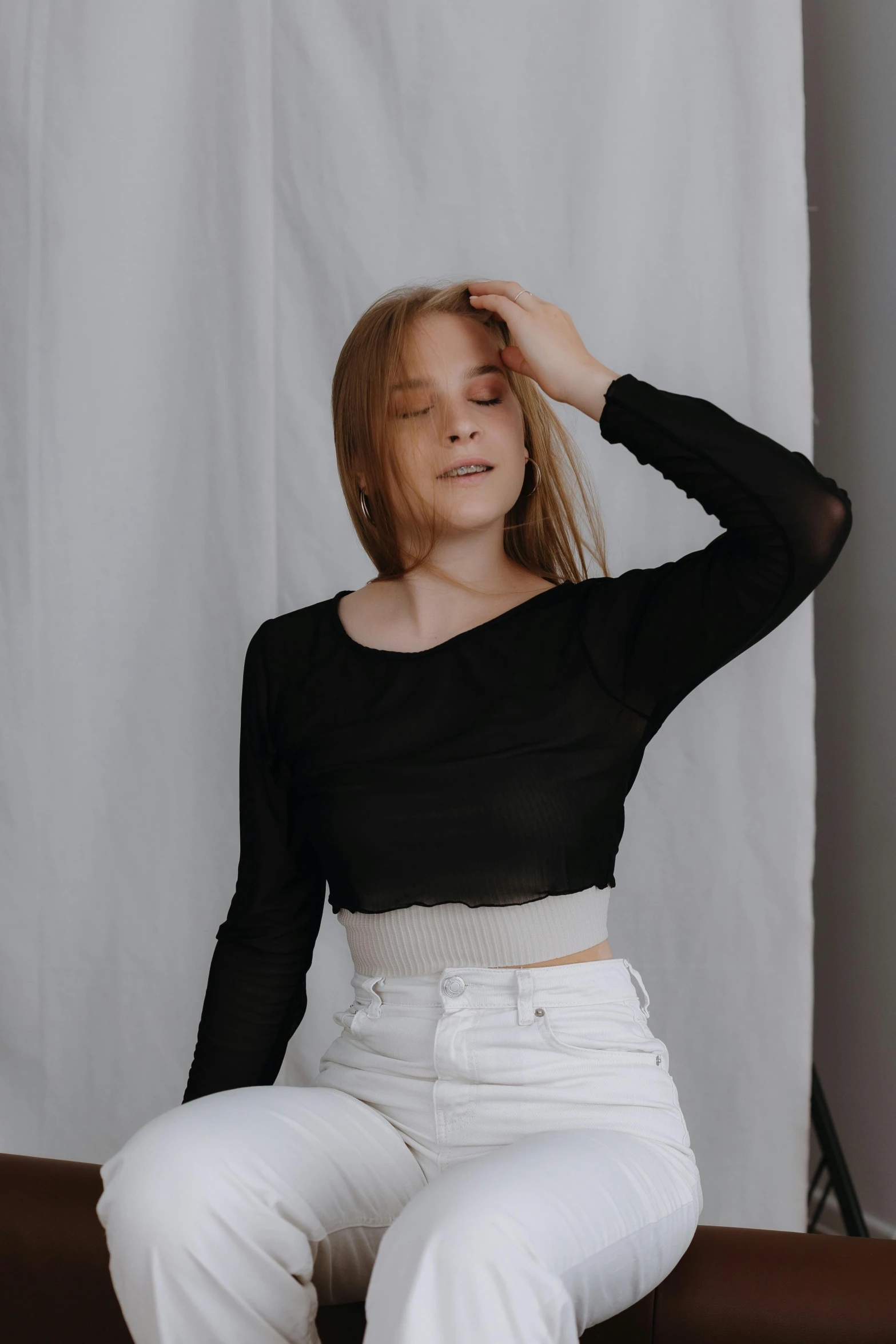 a young woman sitting on a chair with her eyes closed