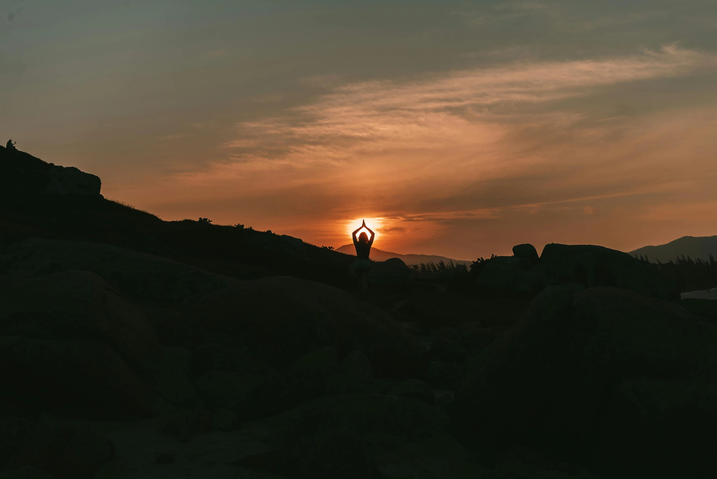 the man stands in front of the sunset, doing an arm stand