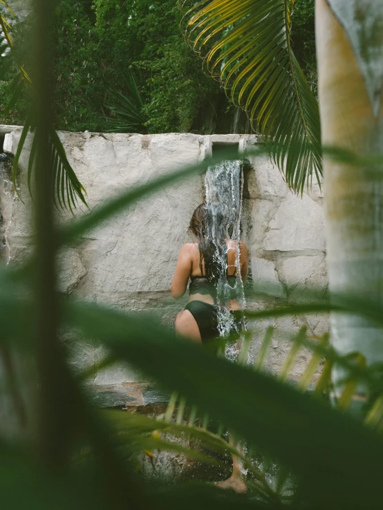 a woman in a bikini sitting by a waterfall