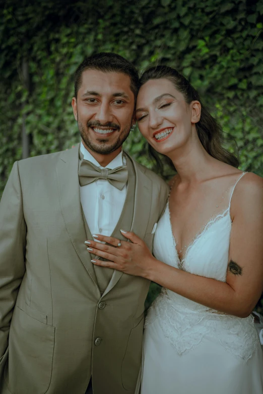 the groom is hugging the bride in front of greenery