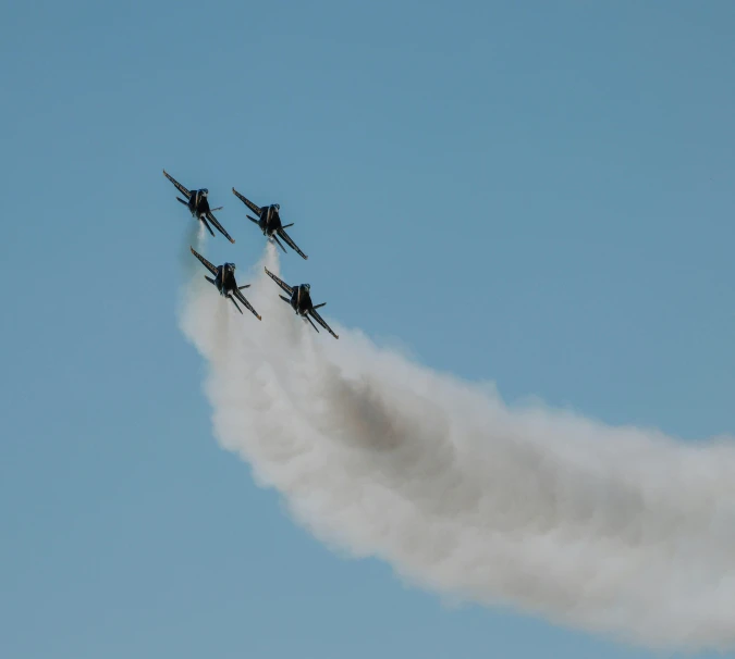 four airplanes performing stunts in formation and smoke billowing in the sky